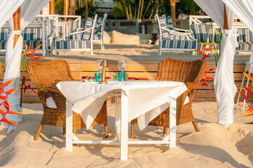 Luxury resort hotel outdoor restaurant on the beach, tropical island cafe, table ready for serving. Summer vacation or holiday, family travel, food, cocktails, relax. Close up