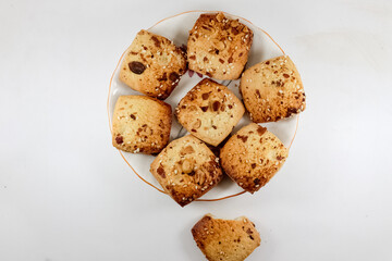 Freshly baked chocolate chips cookies scattered on white background.