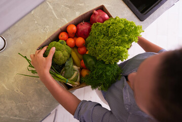 Top view woman received a box full of fresh groceries ordered online by home doorstep delivery....