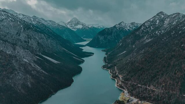 Aerial drone view Plansee lake among snow-capped mountains in Tyrolean Alps, Austria late autumn in cloudy weather. High quality 4k footage