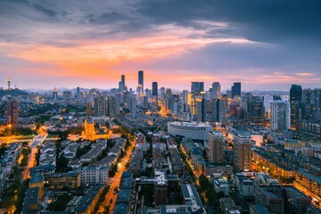 Naklejka na ściany i meble Aerial view of the stunning city skyline illuminated by the setting sun in Dalian, China