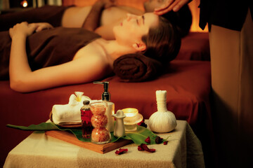 Obraz na płótnie Canvas Aromatherapy massage ambiance or spa salon composition setup with focus decor candles and spa accessories on blur couple enjoying blissful aroma spa massage in resort or hotel background. Quiescent