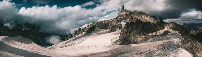 Panoramic shot of the dry rocky mountains reaching to the clouds, Aosta Valley, Italy - obrazy, fototapety, plakaty