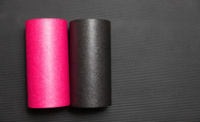 pinke und schwarze Faszienrolle auf schwarzer Isomatte