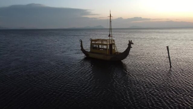 Traditional wood and reed boat called Balsa drifting on Lake Titicaca Bolivia at sunset.