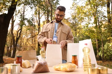 Volunteer packing food products at table in park