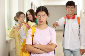 Teen problems. Lonely girl standing separately from other students at school