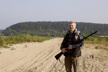 Man with hunting rifle outdoors. Space for text