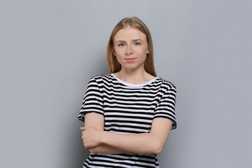 Obraz premium Portrait of beautiful young woman in striped t-shirt on grey background