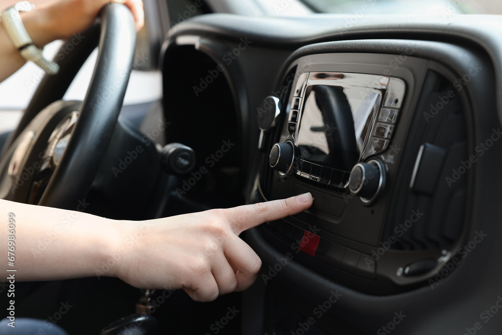 Wall mural Choosing favorite radio. Woman pressing button on vehicle audio in car, closeup