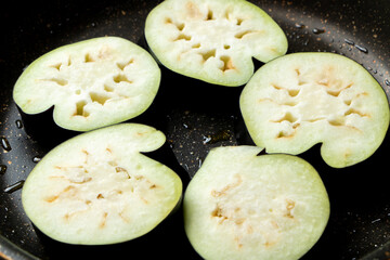 茄子(なす)を輪切りにしてフライパンで焼く調理シーン。(家庭菜園で収穫したいびつな形のナス。)
