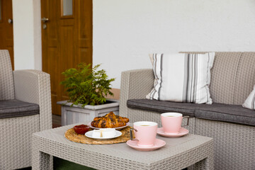 Outdoor breakfast with tea and croissants on rattan table on terrace