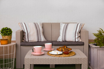 Outdoor breakfast with tea and croissants on rattan table on terrace