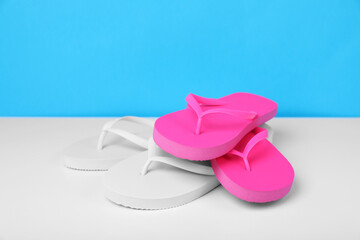 Different flip flops on white table against light blue background