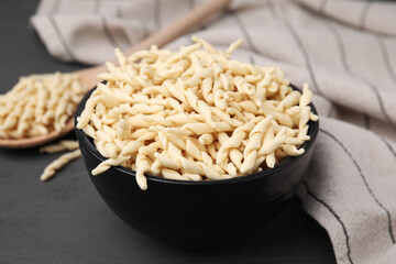 Uncooked trofie pasta in bowl on grey table, closeup