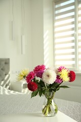 Bouquet of beautiful Dahlia flowers in vase on white table indoors. Space for text