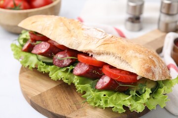 Delicious sandwich with sausages and vegetables on white table, closeup