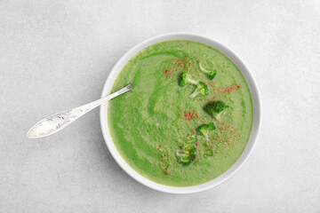 Delicious broccoli cream soup served on light table, top view