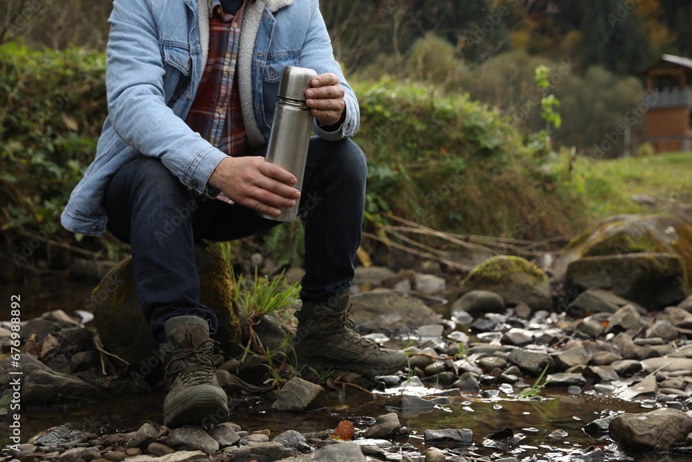 Poster Man with metallic thermos in nature, closeup. Space for text