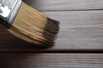 Applying wood stain with brush onto wooden surface, closeup