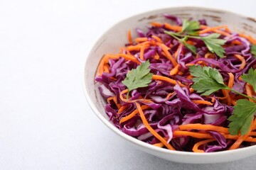 Tasty salad with red cabbage in bowl on white table, closeup. Space for text