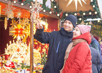 Young couple choosing gift for buying and smiling at Christmas market. 