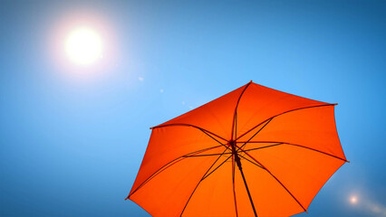 umbrella in the sun against blue sky. Hot summer relaxation and vacation concept