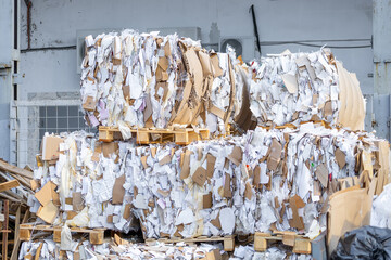 Compressed stacks of recyclable paper, cardboard and plastic film before being sorted at a recycling plant. Wooden pallets. Full frame