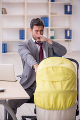 Young male employee looking after newborn at workplace