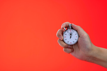 People hand holding stopwatch on red background