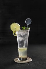 Lemon slush in tall glass with fruit and crushed ice around it on white table with isolated background. Front view. Horizontal composition.
