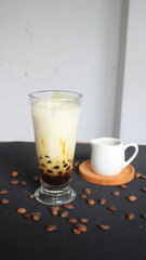 milk coffee in a glass containing boba on a white and black background
