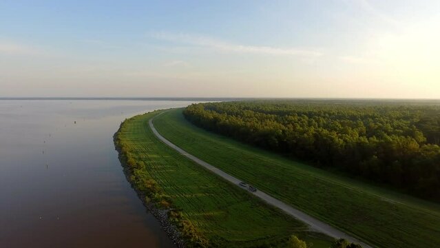 Aerial Shot Of Pickup Truck Towing Nautical Vessel In Meadow, Drone Flying Forward Over River Against Sky - Bayou, Louisiana