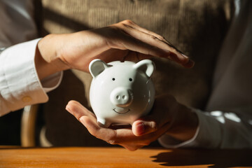 White piggy bank in hand of young man, Saving money for future investment concept. - obrazy, fototapety, plakaty