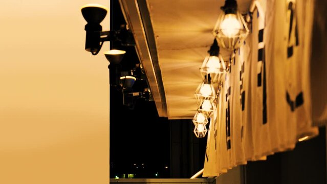 日本の下町の夜。飲食店の入口に掛けられて風に揺れる白いのれん