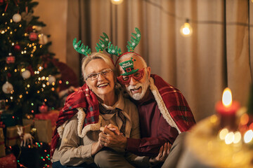 Portrait of a affectionate senior couple sitting at home on Christmas eve and hugging.