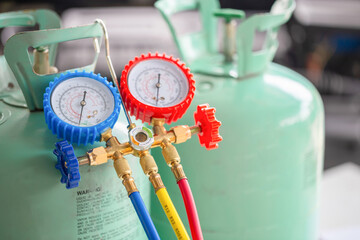 Manifold tool gauge bucket refrigerant applies to car air conditioning with blurred technician...