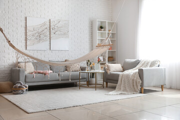 Fototapeta na wymiar Interior of light living room with hammock and grey sofas