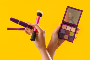 Woman with makeup products on yellow background