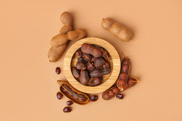 Bowl of tasty tamarinds and seeds on brown background