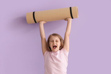 Happy little girl with yoga mat near lilac wall