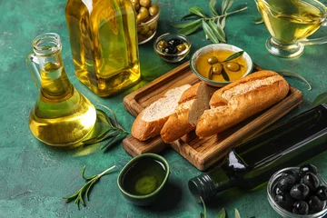 Gordijnen Bowls and glassware of fresh olive oil with bread on green background © Pixel-Shot