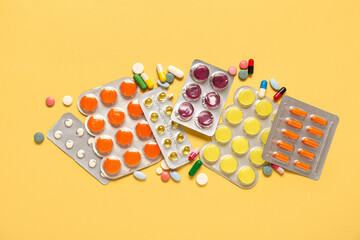 Different pills in blister packs on yellow background