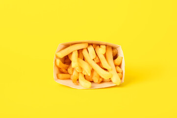 Paper box with delicious french fries on yellow background