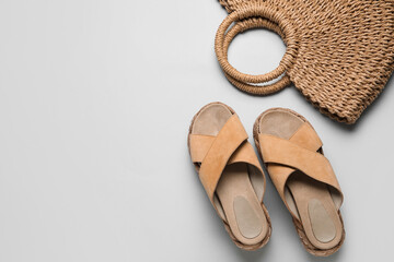 Stylish beige sandals and wicker bag on grey background