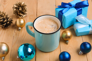 Mug of coffee with gift boxes and Christmas decor on wooden background