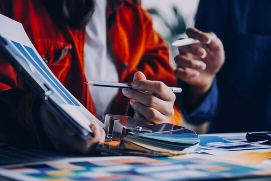 Close up ux developer and ui designer brainstorming about mobile app interface wireframe design on table with customer breif and color code at modern office.Creative digital development agency