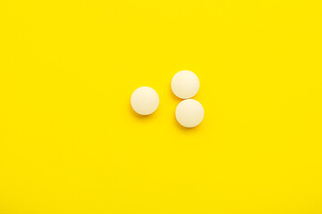 White medical pills on yellow background
