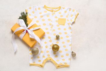 Composition with stylish baby clothes, Christmas gift and balls on light background