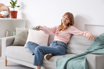 Young woman watching TV on sofa at home